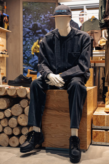 Timberland display. Mannequin sits on top of a pile of logs,