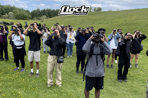 Flock Together Bird Watchers peer through binoculars in a group while standing in a field