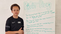 Football Beyond Borders Pitch Plug. Teenage boy stands next to a whiteboard with the words Pitch Plug hand written.