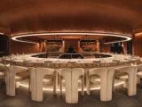 Bar Kar interior. A circular restaurant table with chairs in a warm toned room.