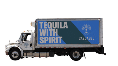 Cazcabel tequila wordmark against a faded white Mexican outdoor wall in daylight